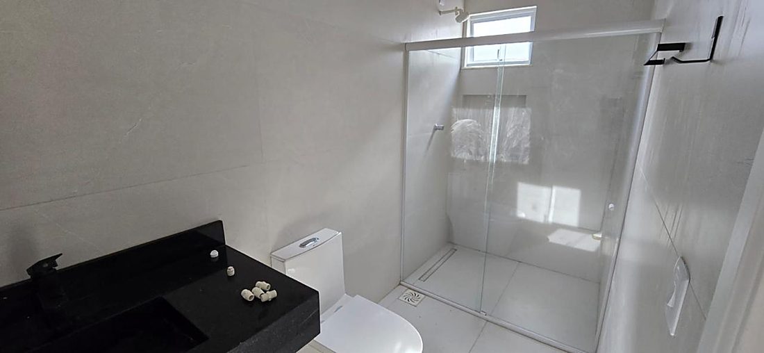 Banheiro da suíte com bancada em granito preto e box de vidro